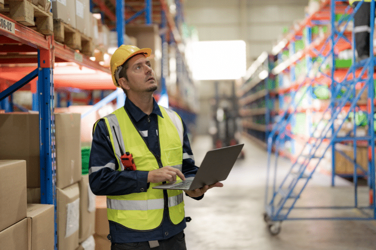 An employee in safety gear reviews a clipboard