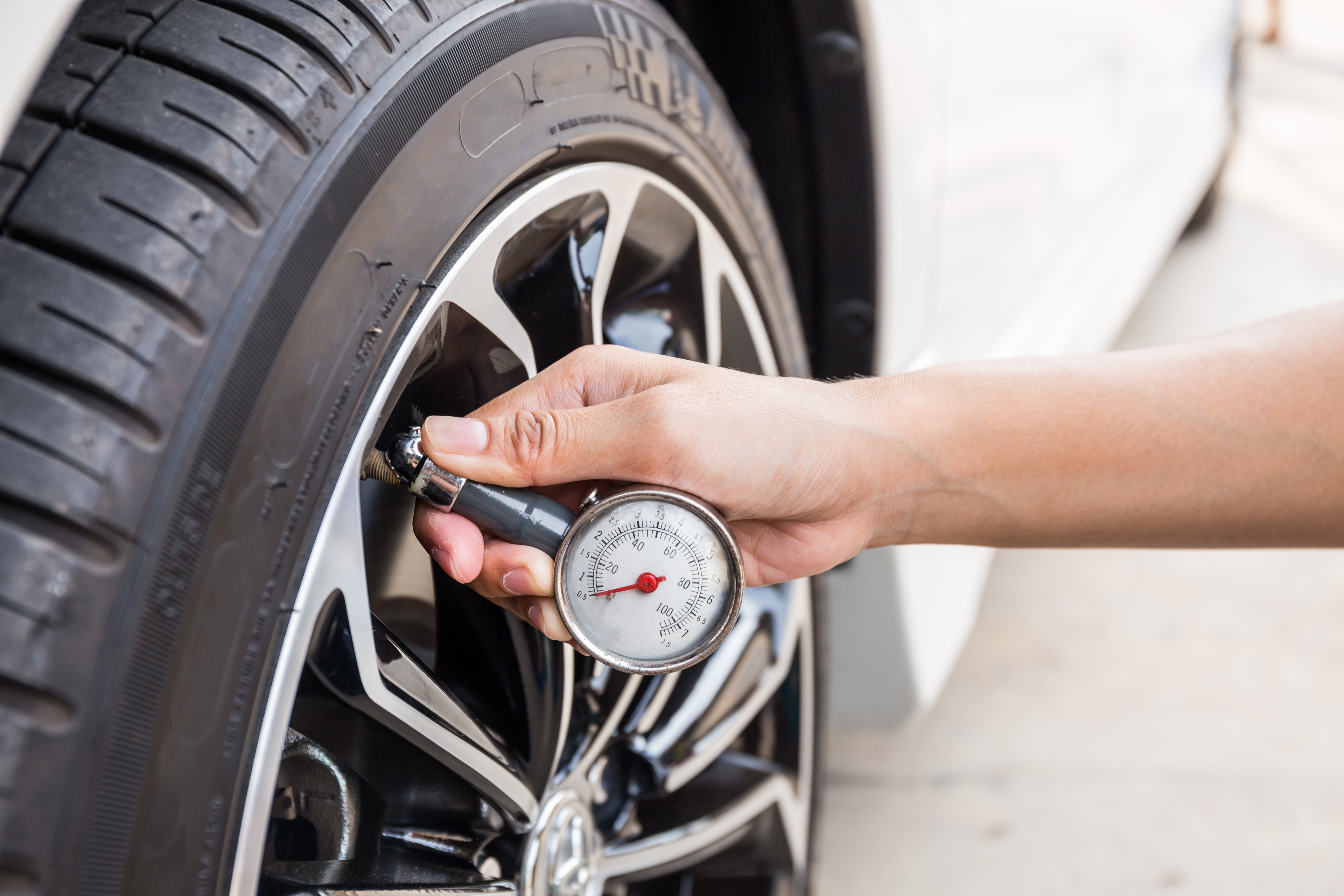 Worker checking tire pressure for a vehicle inspection