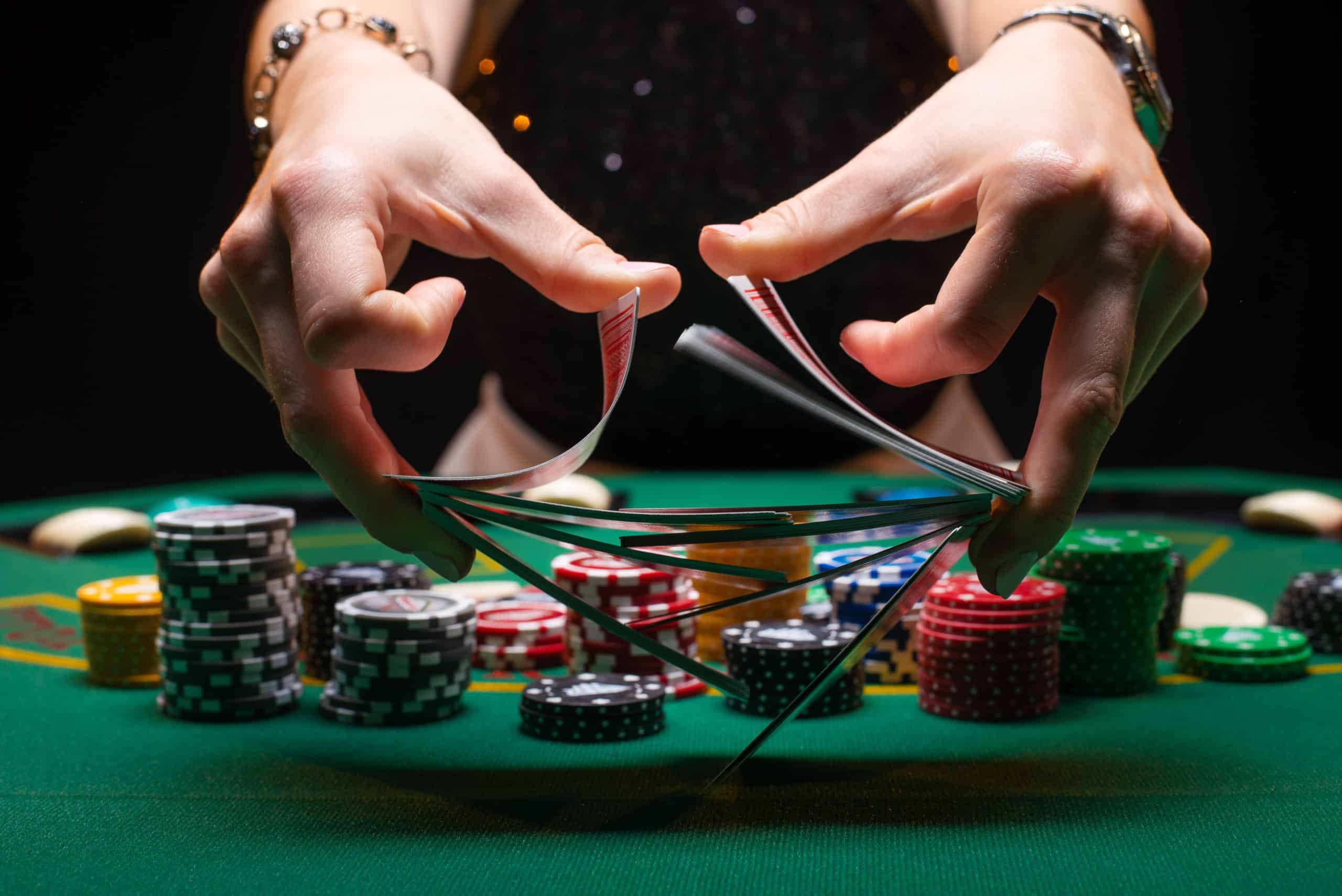 Girl dealer or croupier shuffles poker cards in a casino on the background of a table, chips,.Concept of poker game, game business