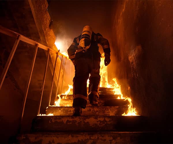 Firefighter climbing stairs in a structure fire