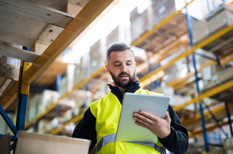 An employee in a safety vest reviews OSHA 300A paperwork on a clipboard.