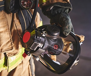 Firefighter holding breathing apparatus.Support firefighter health and wellness with Guardian Tracking.